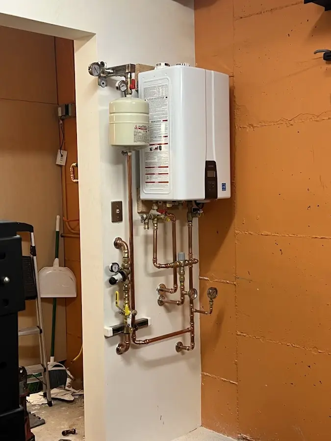 Plumbing technician inspecting water heater connections in Fitchburg
